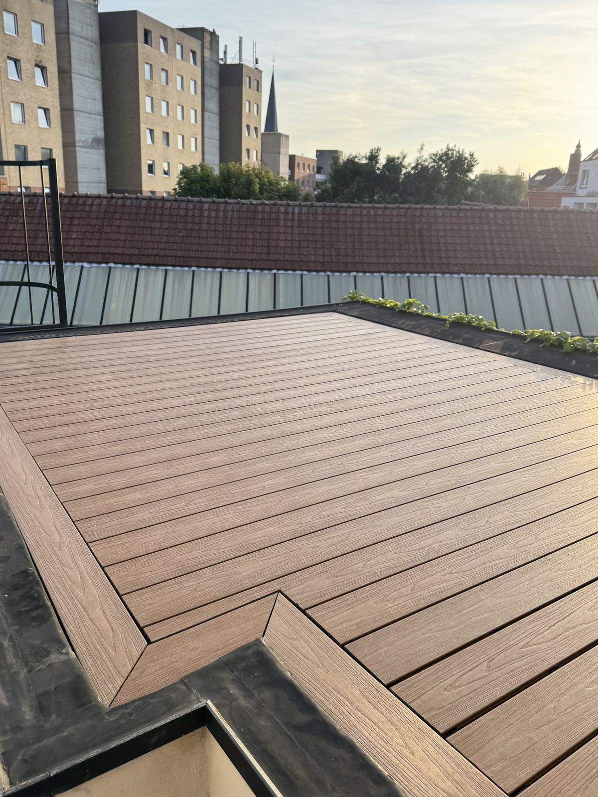 Afgewerkt dakterras in Gent met bruine planken en een omkadering langs de randen